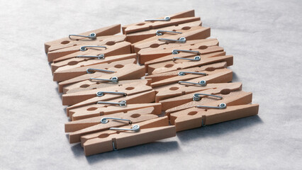 Montón de pinzas de madera para colgar la ropa ordenadas en fila sobre papel blanco