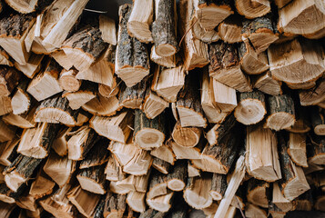 Logs chopped with an ax, dry acacia firewood, spruce for heating lie in a row close-up.