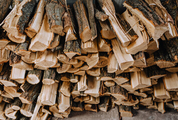Logs chopped with an ax, dry acacia firewood, spruce for heating lie in a row close-up in the forest.