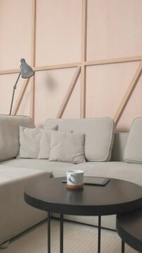 Grey Corner Sofa In The Room With A Wooden Wall And A Black Coffee Table With A Cup