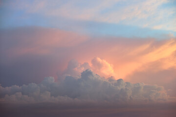 Colorful evening landscape with soft pastel coloured clouds on watercolor tinted sunset sky. Abstract nature background