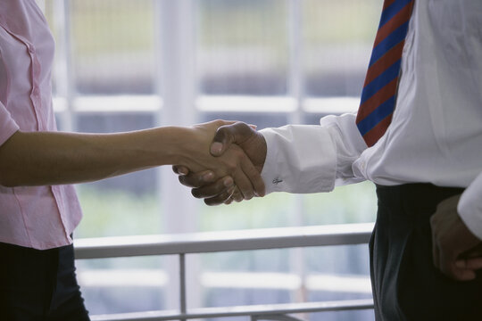 Mid section view of a businessman and a businesswoman shaking hands
