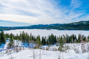 Winter landscape in snow covered Bymarka nature reserve with view of frozen lake Skjellbreia near Trondheim, Norway