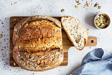 Fresh homemade bread (slice) from whole grain sourdough flour with the addition of bran, seeds (sunflower, pumpkin, flax, sesame) and oatmeal flakes. Healthy food. High quality photo. - obrazy, fototapety, plakaty