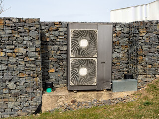 Air conditioning unit against a stone wall.