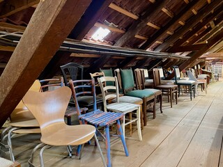 Old wooden attic with vintage chairs.