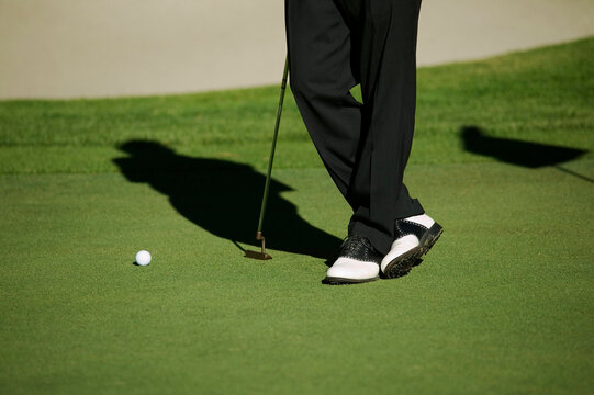 Low section view of a person standing with a golf club