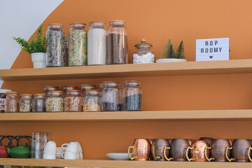 wooden shelves with tea leaves collection and spices in glass jars and vintage tea cups. coffee and tea shops interior