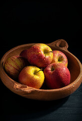 apples in an earthenware bowl on a black background