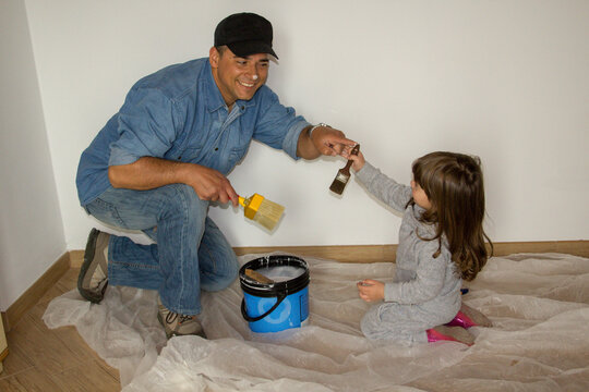 Smiling father and daughter playing together while painting the walls at home