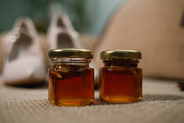 two jars of honey and wooden drizzler on table on yellow background