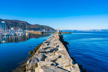 Naklejka premium Skansen guest marina with moored sailboats with Skansen lighthouse at the end of a stone pier, Trondheim, Norway
