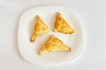 Delicious fragrant triangular baked cakes on a white plate