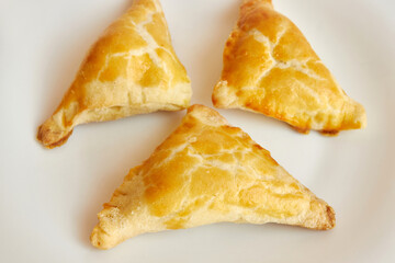 Delicious fragrant triangular baked cakes on a white plate