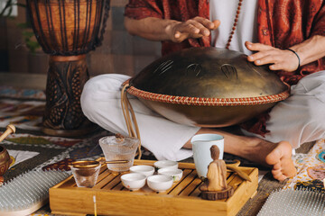 Close-up of a man's hand playing a modern musical instrument - the Orion tongue drum during the tea...