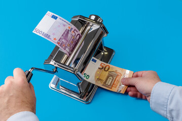 Inflation concept represented in a paste reduction machine that converts a 500 € bill into a 50...
