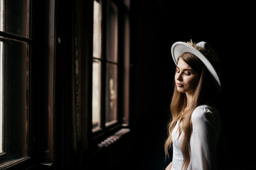 The bride in a hat and a bouquet. Portrait of a bride in a white dress. Portrait of the bride. Young girl in a white wedding dress and hat with a bouquet of flowers.