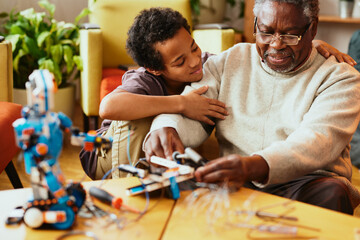 A granddad and his grandchild building a robot at home.