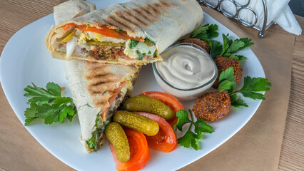 Plate of falafel with pita bread, vegetables and tzatziki sauce. Arabian meal, hummus and falafel.