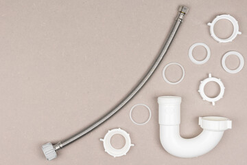 Plumbing supplies, pipes, and gaskets displayed in a flat layout on a tan background