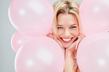 Im not sure why but Im so happy. Cropped shot of a beautiful young woman posing with pink balloons.