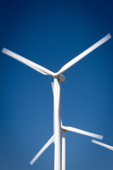 Tightly framed Wind turbine creating a unique geometric pattern. Blades appear to be slightly in motion. Blue sky background. Portrait orientation. 