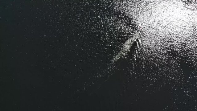 Luftaufnahme von Motorboot fahrend auf Wasser mit Wellen zwischen Inseln mit B&auml;umen in Schweden auf See bei Sonne per Drohne gefilmt