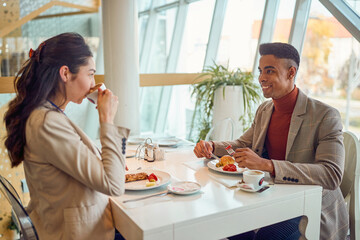 A young businessman is chatting with his young female colleaguea during a lunch break in the canteen. Business, people, company