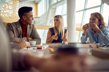 A young business man is chatting with female colleagues during a lunch break in the company...