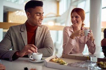 A young businessman is chatting with female colleague while they enjoying coffee after a lunch in the company building together. Business, people, company