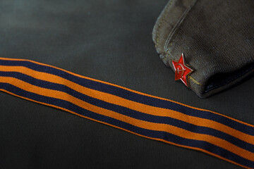 Headdress of the Soviet Army Pilotka on the background of the St. George ribbon and army fabric.