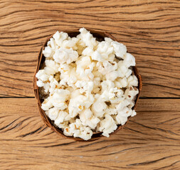 Popcorns in a basket over wooden table