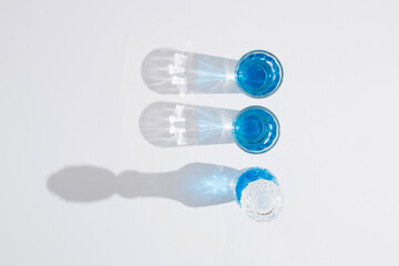 Blue alcoholic drink into small glasses on white background.