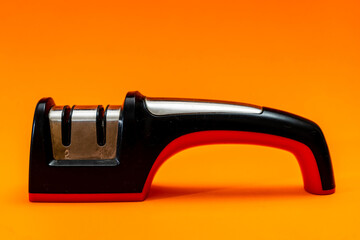 Knife sharpener isolated on an orange background. Non-professional kitchen utensil.