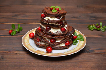 stack of chocolate pancakes with berries on wooden background