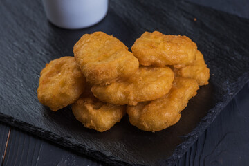 Nuggets on a black tray with garlic sauce