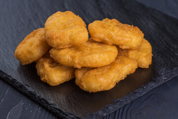 Nuggets on a black tray with garlic sauce