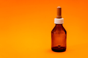 Small bottle with amber glass dropper insulated on orange background.