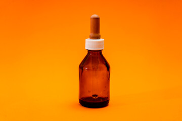 Small bottle with amber glass dropper insulated on orange background.