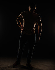 Fototapeta na wymiar Silhouette of a guy posing in studio while standing and holding his posture