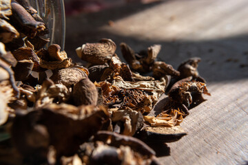 Dried mushrooms scattered with jars on a wooden table.