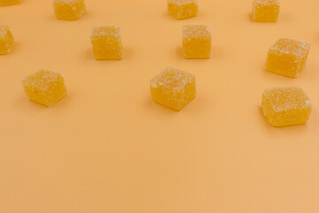 Candy orange marmalade in the form of cubes on an orange background. Flat ley