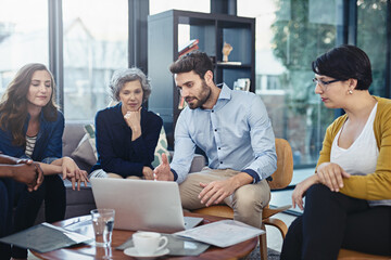 Partners in creativity. Cropped shot of a group of designers working on a laptop during a meeting in the office.