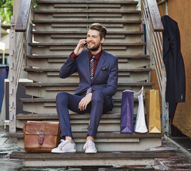 Dressed in his best for a day of retail therapy. Shot of a well dressed young man using his phone on a shopping spree.