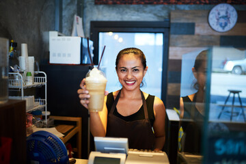 Fototapeta na wymiar Heres your order. Portrait of a young barista holding up a chilled coffee beverage in a coffee shop.