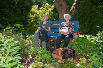 zwei seniorinnen sitzen im schatten auf einer bank