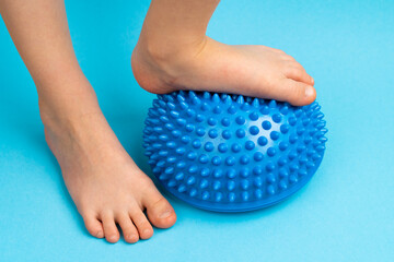 children's feet with a blue balancer on a light blue background, treatment and prevention of flat...