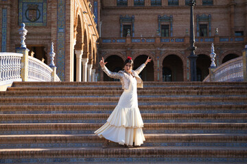 Flamenco dancer, woman, brunette and beautiful typical spanish dancer is dancing and clapping her hands on the stairs of a square in seville. Flamenco concept of cultural heritage of humanity.