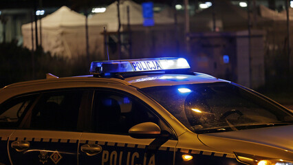 Radiowóz policji na sygnale wieczorem w mieście alarmowo do wypadku na światłach. - obrazy, fototapety, plakaty