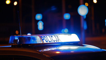 Radiowóz policji na sygnale wieczorem w mieście alarmowo do wypadku na światłach. - obrazy, fototapety, plakaty